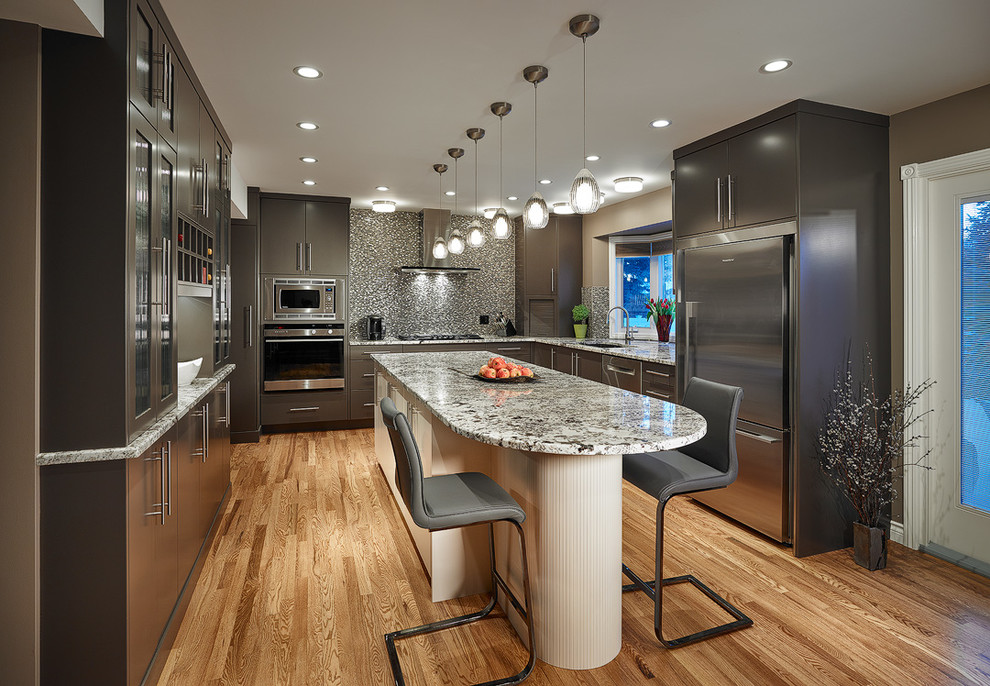 This is an example of a large contemporary u-shaped eat-in kitchen in Calgary with an undermount sink, flat-panel cabinets, brown cabinets, granite benchtops, light hardwood floors, with island, beige splashback, glass tile splashback and stainless steel appliances.