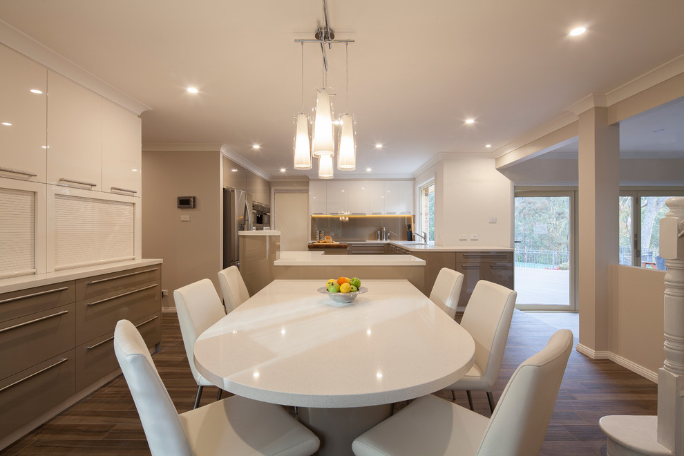 This is an example of an expansive contemporary u-shaped eat-in kitchen in Sydney with an undermount sink, flat-panel cabinets, green cabinets, quartz benchtops, brown splashback, glass sheet splashback, stainless steel appliances, ceramic floors and multiple islands.