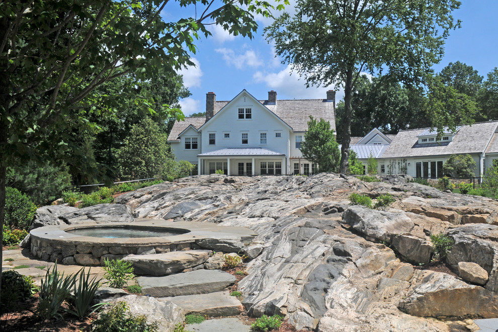 Expansive country backyard round natural pool in New York with a hot tub and natural stone pavers.