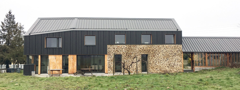 Cette photo montre une très grande façade de maison noire tendance à deux étages et plus avec un revêtement mixte, un toit à deux pans, un toit en métal et un toit gris.