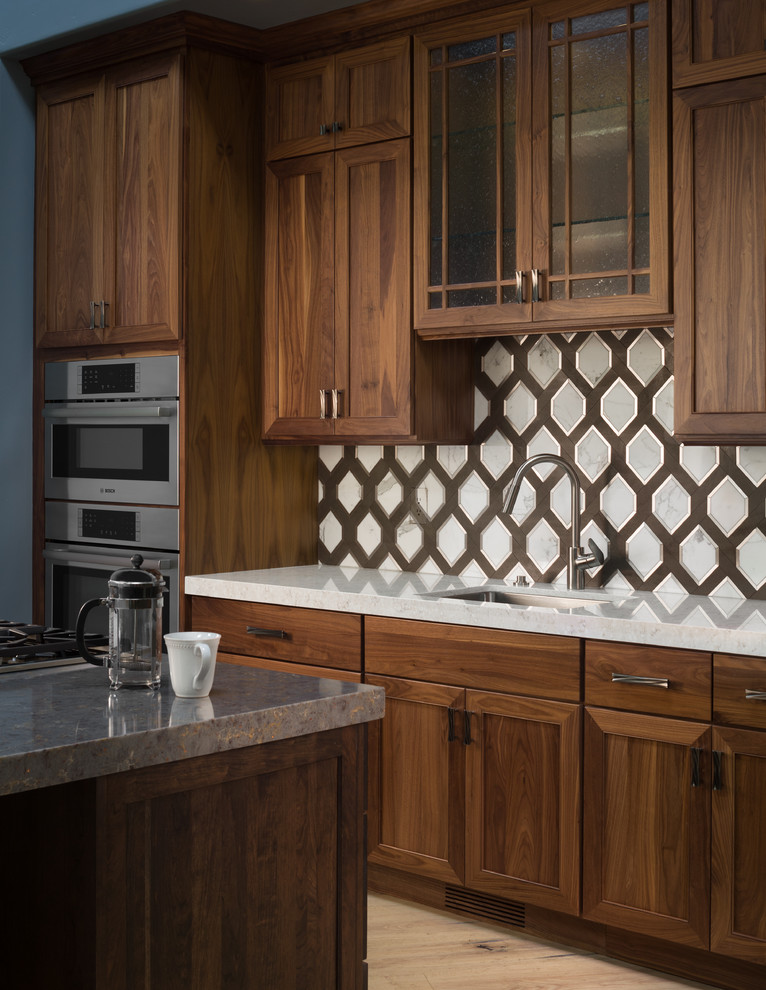 Inspiration for a mid-sized transitional galley light wood floor and beige floor eat-in kitchen remodel in San Francisco with a double-bowl sink, dark wood cabinets, quartzite countertops, white backsplash, ceramic backsplash, stainless steel appliances and an island