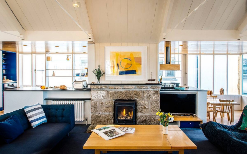 Design ideas for a medium sized contemporary open plan living room in Cornwall with white walls, carpet, a wood burning stove, a stone fireplace surround, a built-in media unit, blue floors, tongue and groove walls and feature lighting.