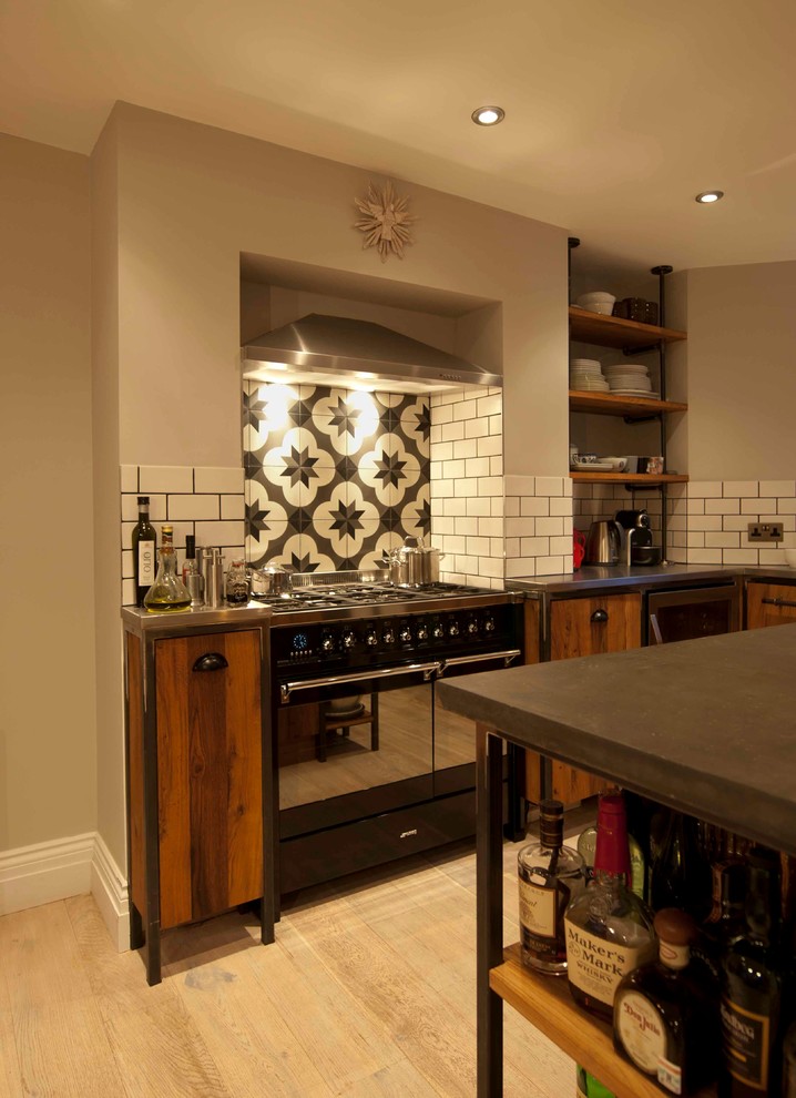 This is an example of a mid-sized industrial u-shaped eat-in kitchen in London with an undermount sink, flat-panel cabinets, grey cabinets, concrete benchtops, white splashback, ceramic splashback, stainless steel appliances, light hardwood floors and with island.