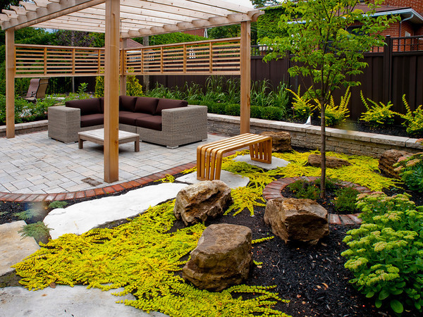 Photo of a large contemporary backyard patio in Montreal with a water feature, brick pavers and a pergola.