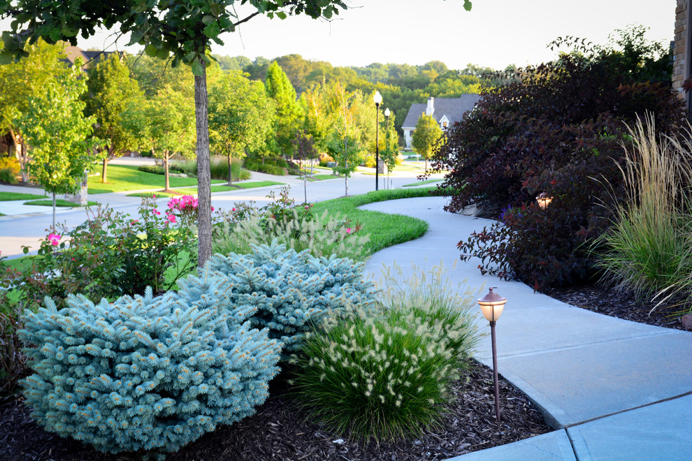 This is an example of a mid-sized rustic partial sun front yard concrete paver landscaping in Omaha.