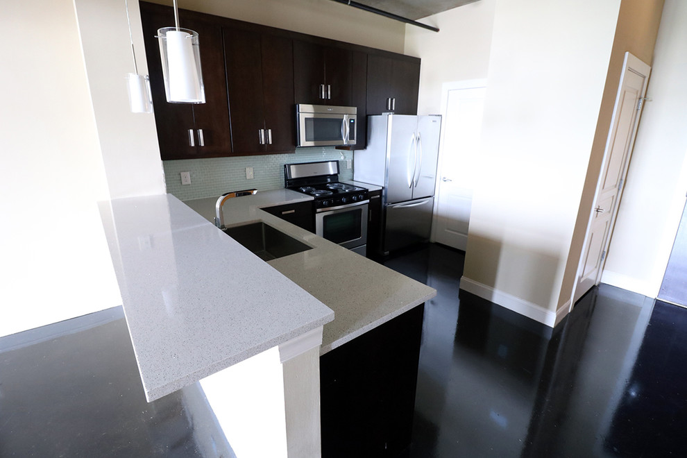 Home design - huge contemporary l-shaped concrete floor home design idea in Charlotte with a single-bowl sink, flat-panel cabinets, dark wood cabinets, quartzite countertops, blue backsplash, mosaic tile backsplash, stainless steel appliances and no island