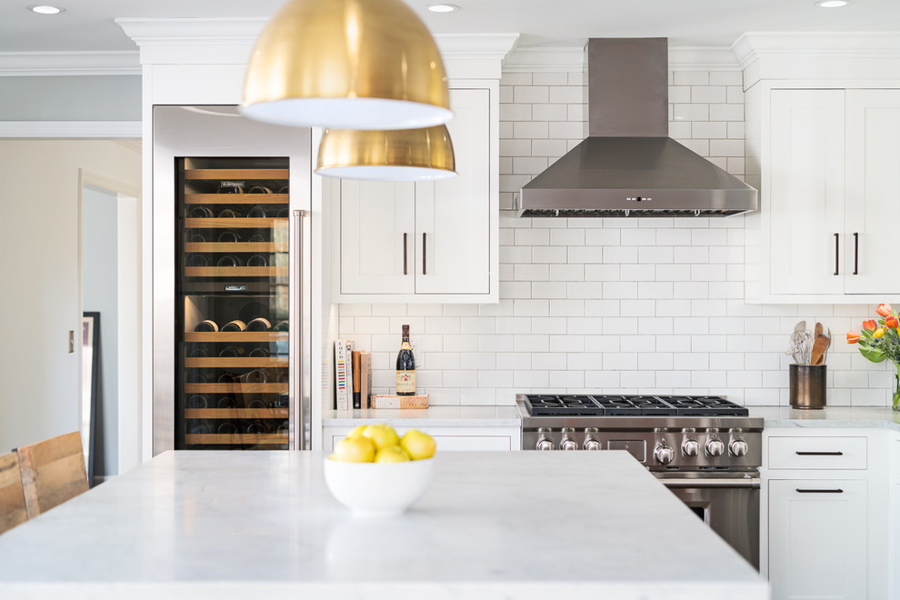 Inspiration for a large transitional l-shaped open plan kitchen in New York with an undermount sink, shaker cabinets, white cabinets, marble benchtops, white splashback, subway tile splashback, stainless steel appliances, medium hardwood floors, with island, brown floor and white benchtop.