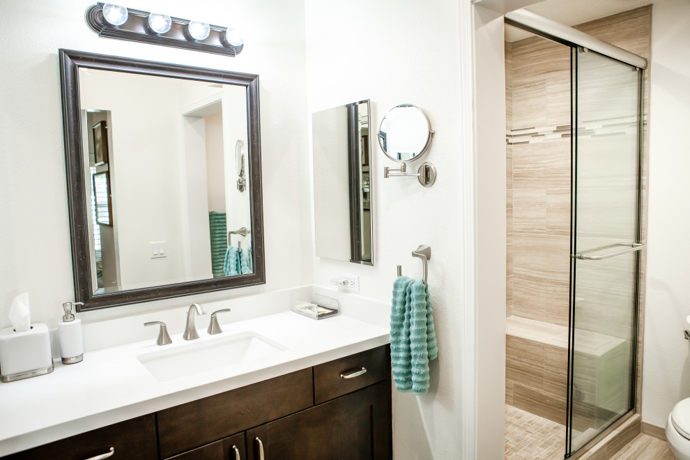 Photo of a small modern ensuite bathroom in Los Angeles with flat-panel cabinets, dark wood cabinets, an alcove shower, a two-piece toilet, beige tiles, porcelain tiles, white walls, porcelain flooring, a submerged sink, engineered stone worktops, beige floors, a sliding door, white worktops, a single sink and a built in vanity unit.