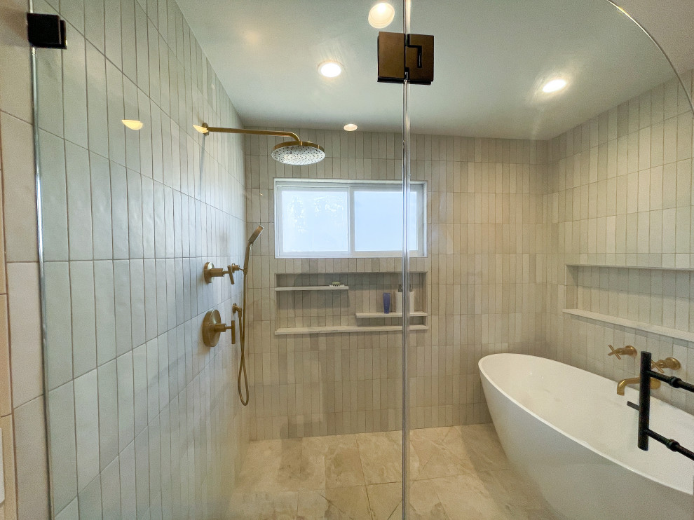 This is an example of a medium sized modern ensuite bathroom in Los Angeles with flat-panel cabinets, medium wood cabinets, a freestanding bath, a walk-in shower, a one-piece toilet, grey tiles, metro tiles, white walls, porcelain flooring, a built-in sink, quartz worktops, beige floors, a hinged door, white worktops, a wall niche, double sinks, a built in vanity unit and a vaulted ceiling.