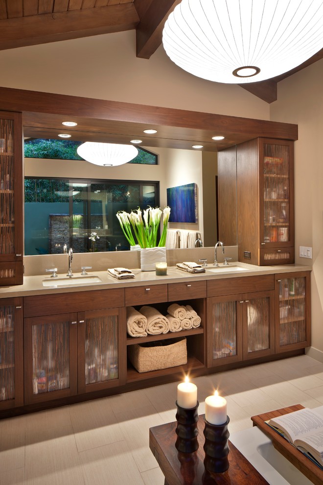 This is an example of a large midcentury master bathroom in Los Angeles with glass-front cabinets, medium wood cabinets, beige walls, ceramic floors, an undermount sink, granite benchtops and beige floor.