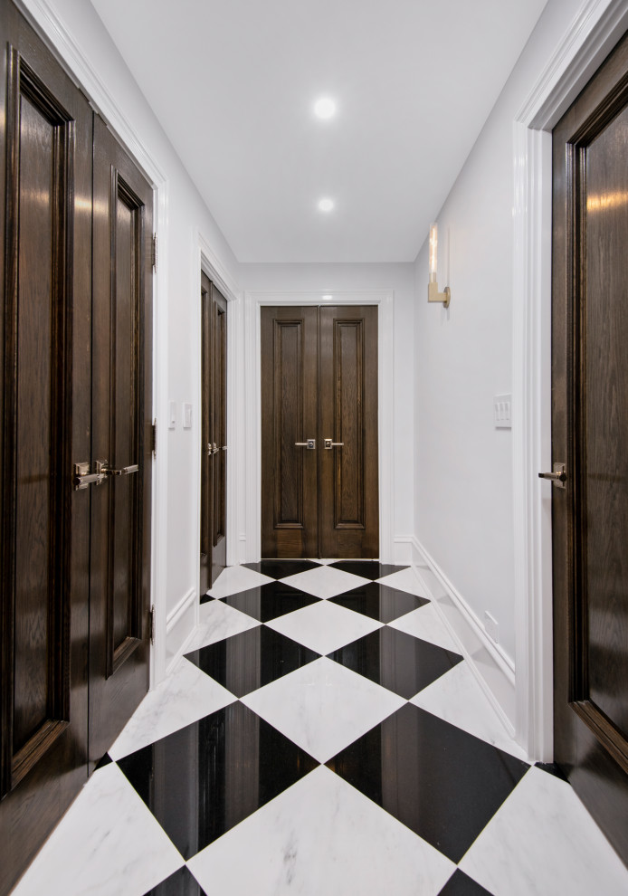 Aménagement d'un grand hall d'entrée classique avec un mur gris, un sol en marbre, une porte double, une porte en bois foncé, un sol multicolore, un plafond à caissons et du lambris.