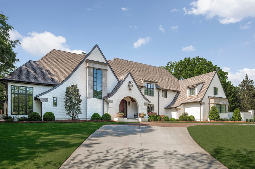 Photo of a large country three-storey brick white house exterior in Charlotte with a shingle roof.
