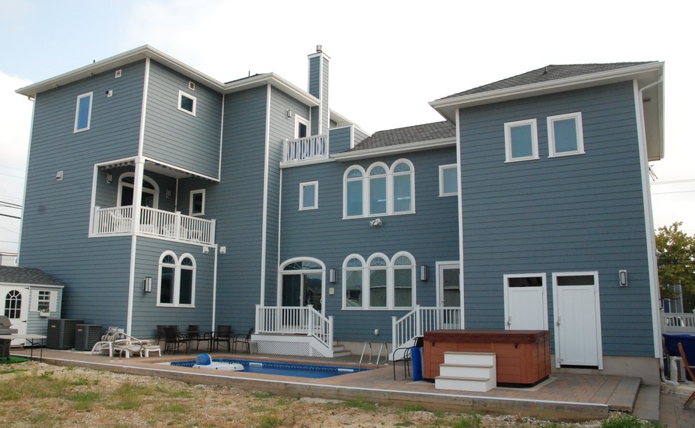 Photo of a large mediterranean three-storey blue exterior in New York with wood siding.