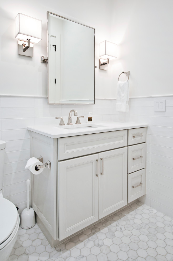 Photo of a mid-sized transitional kids bathroom in Nashville with recessed-panel cabinets, white cabinets, an alcove shower, white tile, white walls, an undermount sink, engineered quartz benchtops, white floor, a hinged shower door and white benchtops.