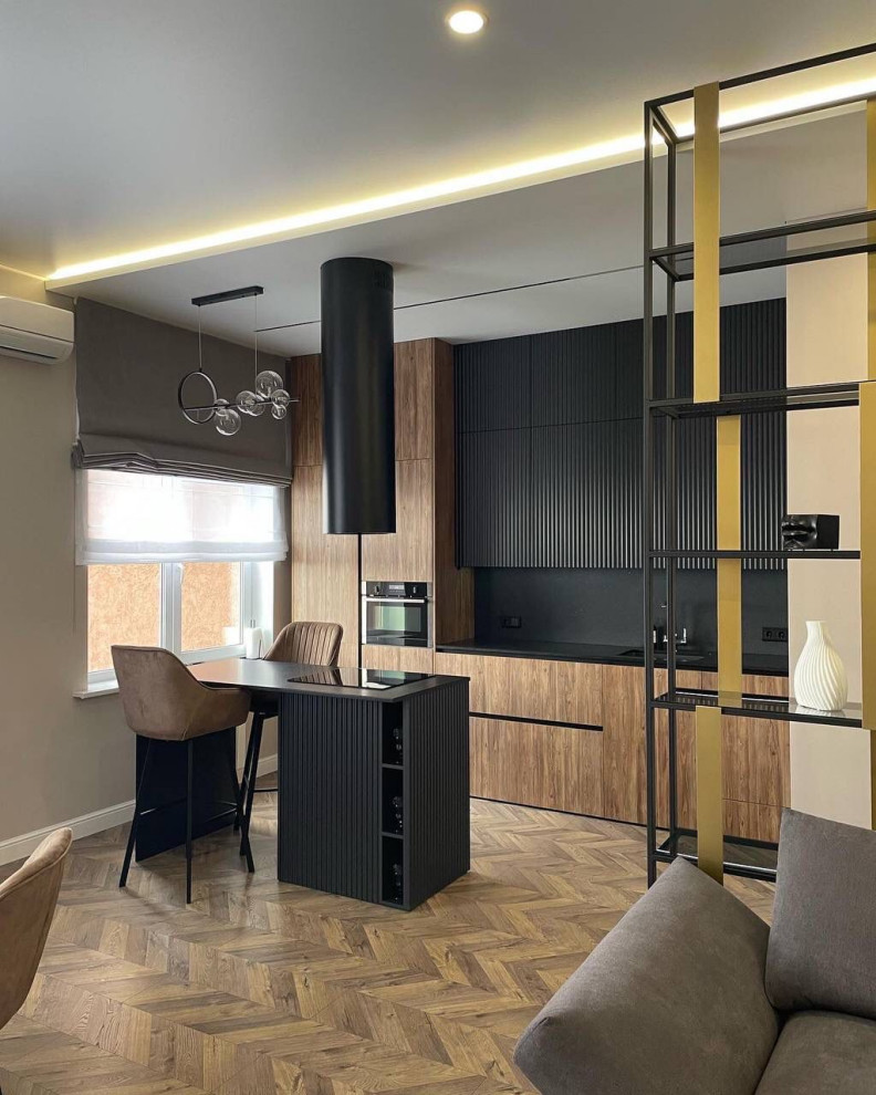 Small contemporary single-wall open plan kitchen in Moscow with a submerged sink, flat-panel cabinets, black cabinets, engineered stone countertops, black splashback, engineered quartz splashback, black appliances, medium hardwood flooring, an island, brown floors, black worktops, a drop ceiling and feature lighting.