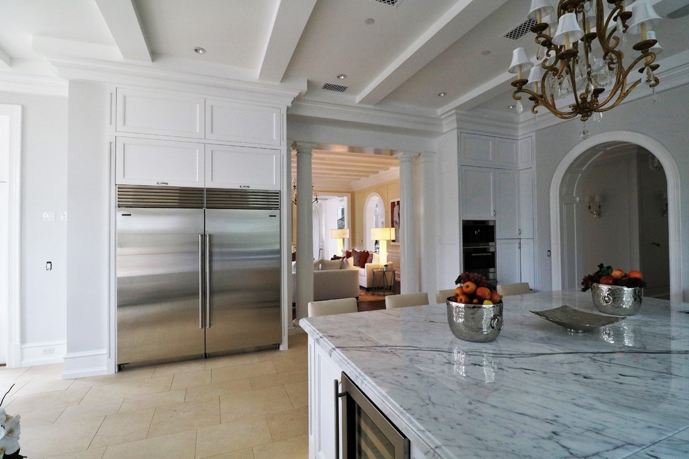 Inspiration for a transitional kitchen in Los Angeles with white cabinets, with island, shaker cabinets, marble benchtops and limestone floors.