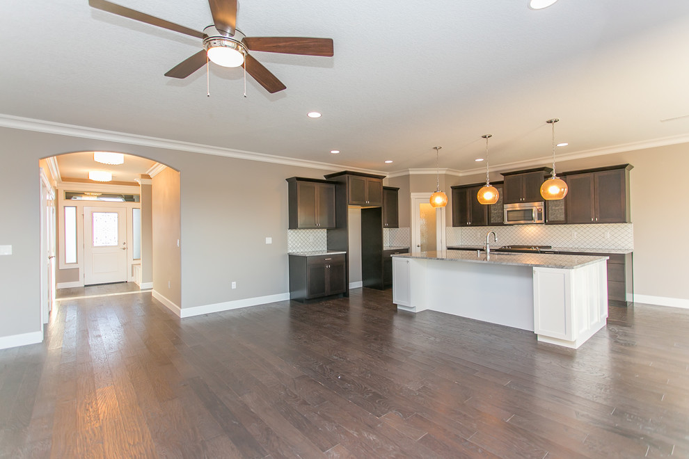 Open concept kitchen - mid-sized transitional l-shaped dark wood floor open concept kitchen idea in Seattle with an undermount sink, shaker cabinets, dark wood cabinets, granite countertops, white backsplash, porcelain backsplash, stainless steel appliances and an island