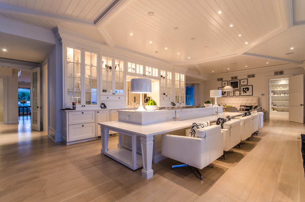 Large tropical galley kitchen in Miami with glass-front cabinets, white cabinets, quartz benchtops, panelled appliances, light hardwood floors and with island.