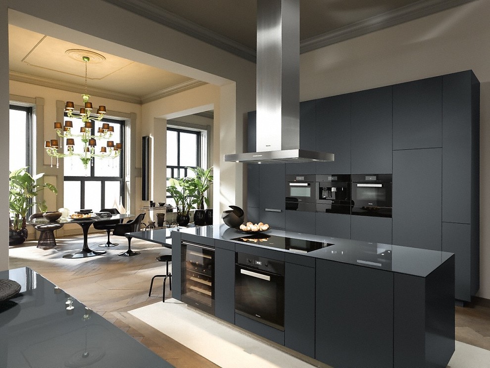 Photo of an expansive contemporary galley open plan kitchen in Toulouse with flat-panel cabinets, black cabinets, black appliances, with island, brown floor and black benchtop.