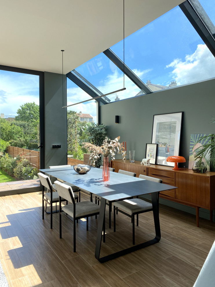 Idee per una sala da pranzo aperta verso il soggiorno minimal con pareti verdi, pavimento in legno massello medio e pavimento marrone