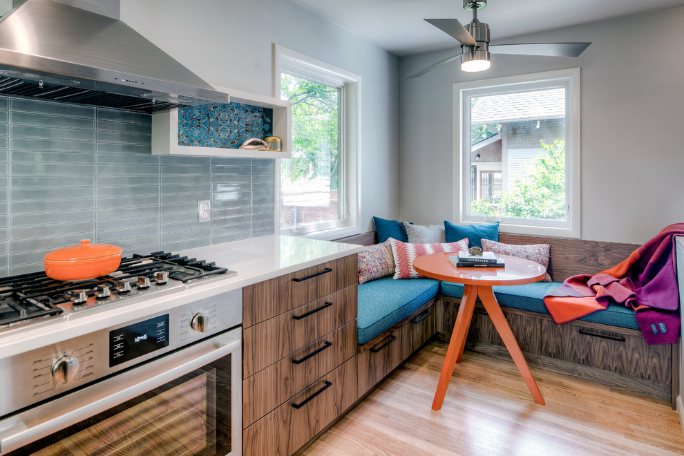 Photo of a contemporary eat-in kitchen in Portland with flat-panel cabinets, dark wood cabinets, grey splashback, stainless steel appliances, medium hardwood floors, brown floor and white benchtop.