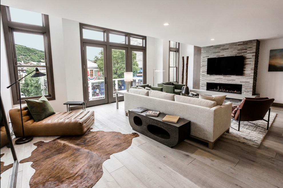 Photo of a small contemporary open concept living room in Salt Lake City with light hardwood floors, a standard fireplace, a tile fireplace surround and a wall-mounted tv.