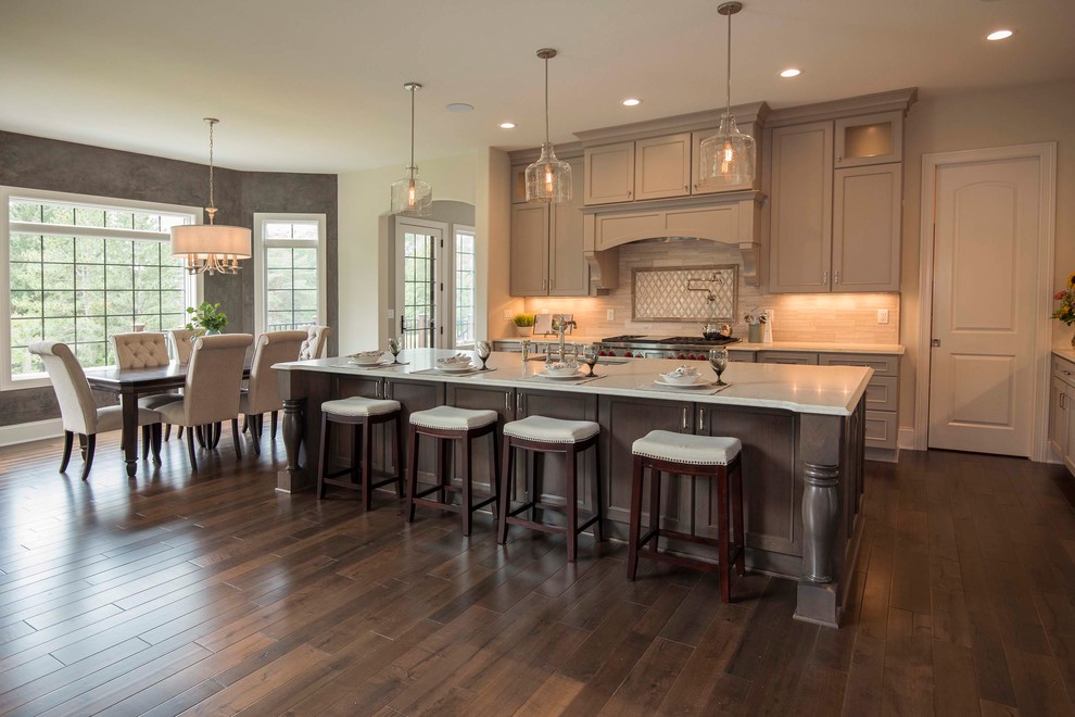 Large traditional u-shaped eat-in kitchen in Milwaukee with an undermount sink, recessed-panel cabinets, grey cabinets, ceramic splashback, stainless steel appliances, dark hardwood floors, with island, brown floor, white benchtop, marble benchtops and beige splashback.