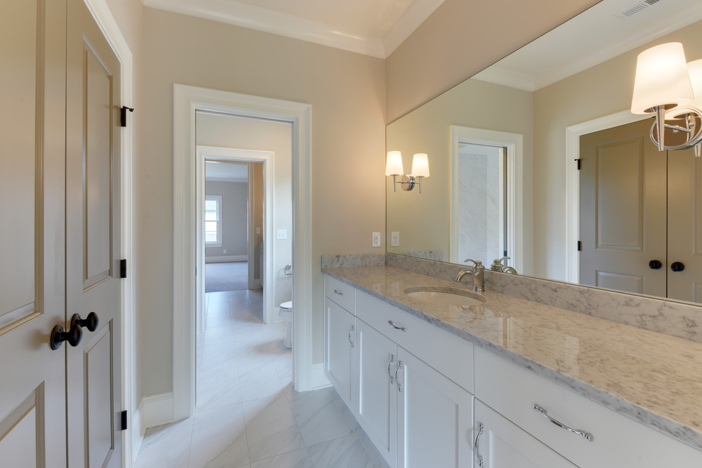 Example of a mid-sized transitional master gray tile and ceramic tile ceramic tile freestanding bathtub design in Charlotte with recessed-panel cabinets, white cabinets, beige walls, an undermount sink and marble countertops