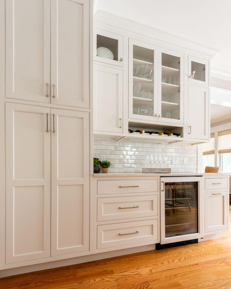Eat-in kitchen - large transitional u-shaped medium tone wood floor and brown floor eat-in kitchen idea in Boston with an undermount sink, shaker cabinets, white cabinets, quartz countertops, gray backsplash, subway tile backsplash, stainless steel appliances, an island and black countertops