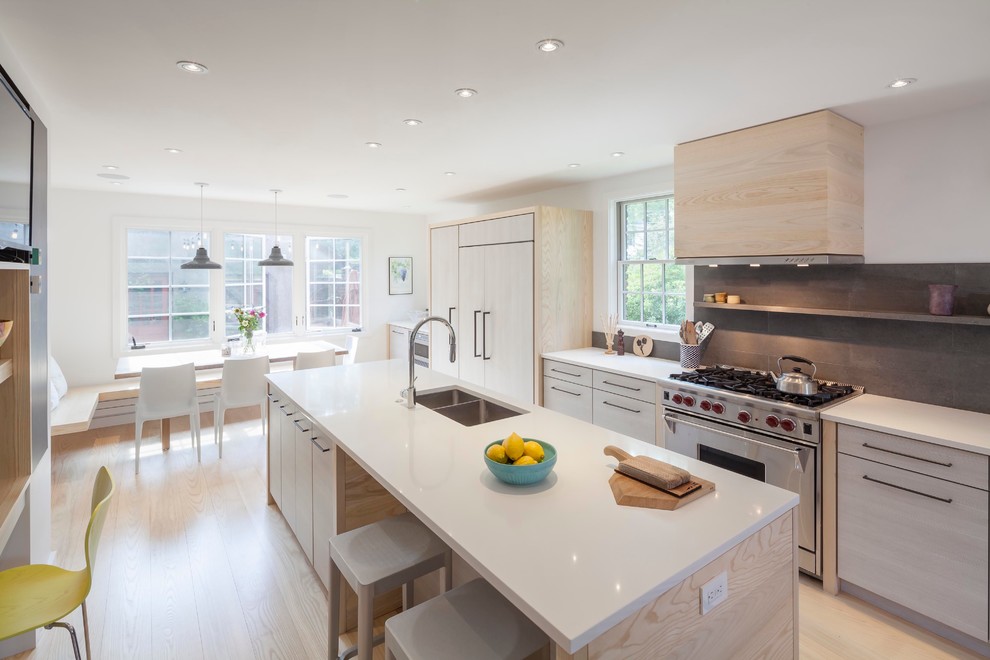 Design ideas for a contemporary galley eat-in kitchen in Boston with a double-bowl sink, flat-panel cabinets, light wood cabinets, grey splashback, stainless steel appliances, light hardwood floors, with island and stone tile splashback.