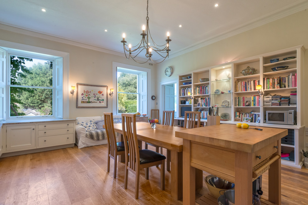 This is an example of an expansive country l-shaped eat-in kitchen in Devon with an undermount sink, recessed-panel cabinets, white cabinets, white splashback, ceramic splashback, coloured appliances, medium hardwood floors and with island.