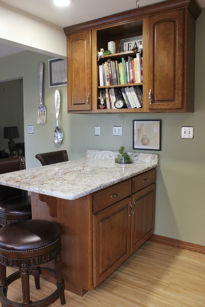 Photo of a small traditional l-shaped eat-in kitchen in Other with an undermount sink, raised-panel cabinets, medium wood cabinets, granite benchtops, stainless steel appliances, bamboo floors and a peninsula.