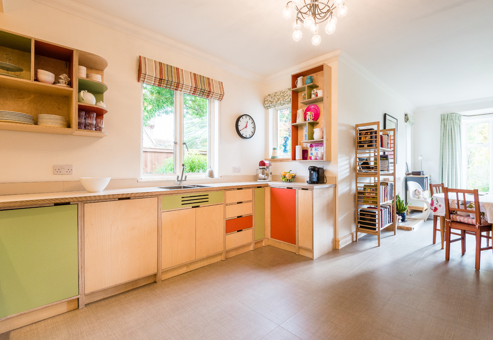 This is an example of a mid-sized midcentury u-shaped open plan kitchen in Other with a double-bowl sink, light wood cabinets, wood benchtops, green splashback, glass sheet splashback and stainless steel appliances.