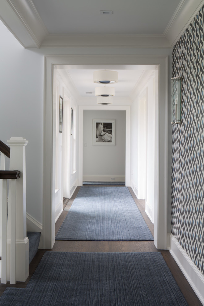 This is an example of a beach style hallway in New York with white walls and dark hardwood floors.