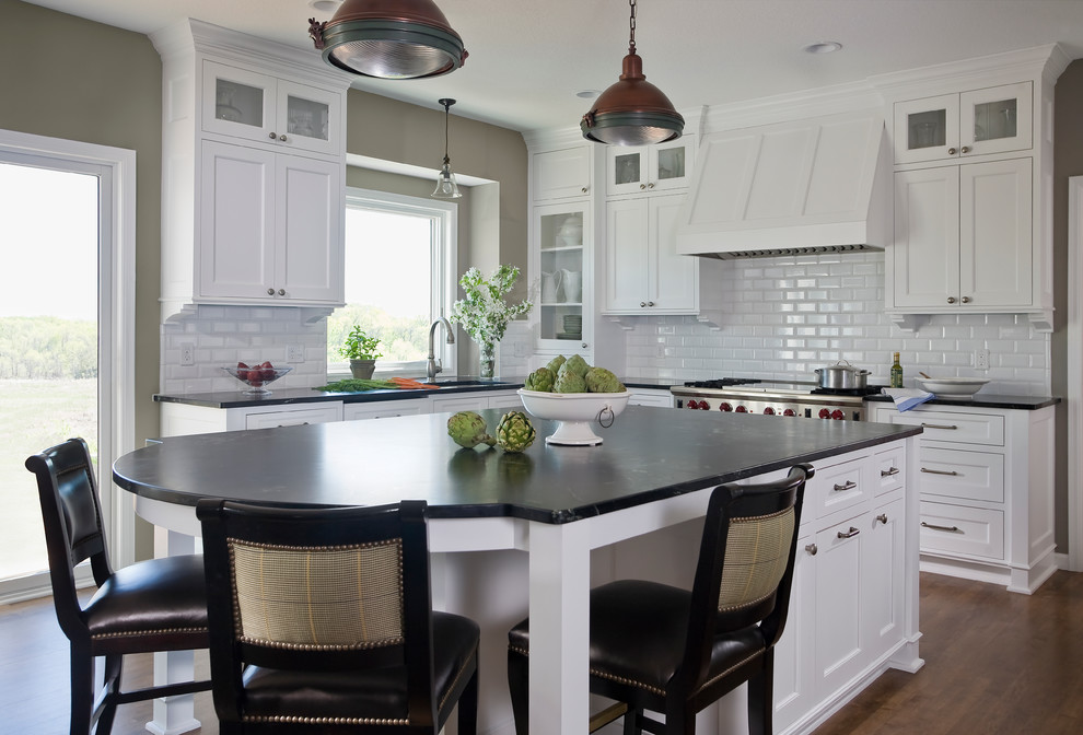 Inspiration for a mid-sized traditional l-shaped kitchen in Minneapolis with an undermount sink, flat-panel cabinets, white cabinets, white splashback, stainless steel appliances, medium hardwood floors, ceramic splashback, with island and soapstone benchtops.