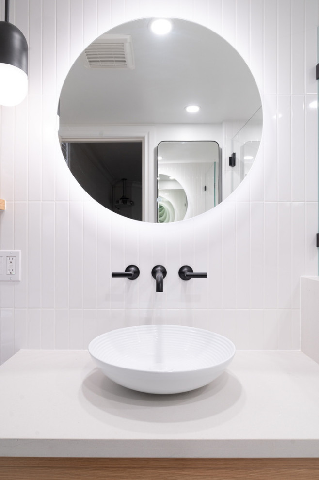This is an example of a medium sized contemporary bathroom in Vancouver with recessed-panel cabinets, light wood cabinets, an alcove shower, a one-piece toilet, white tiles, porcelain tiles, porcelain flooring, a vessel sink, quartz worktops, white floors, a hinged door, white worktops, a wall niche, a single sink and a floating vanity unit.