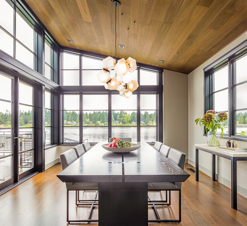 Foto di una sala da pranzo aperta verso la cucina contemporanea con pavimento in legno massello medio e soffitto in legno