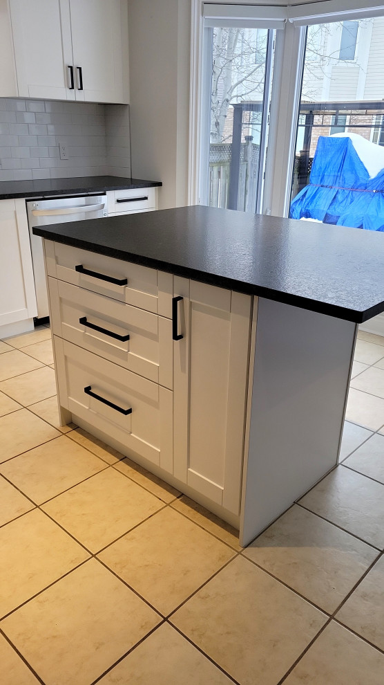 Kitchen - transitional kitchen idea with recessed-panel cabinets, white cabinets, granite countertops, gray backsplash, porcelain backsplash, an island and black countertops