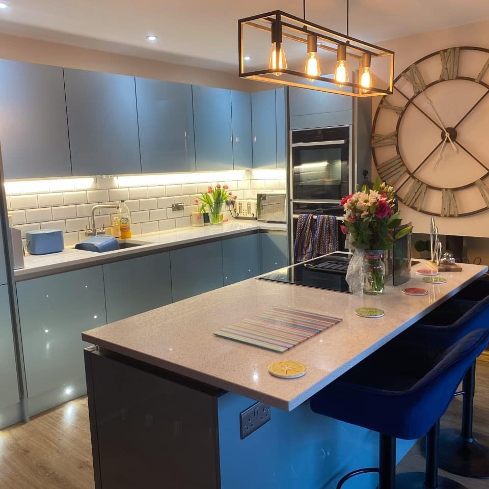 Inspiration for a medium sized contemporary open plan kitchen with a submerged sink, flat-panel cabinets, turquoise cabinets, quartz worktops, white splashback, metro tiled splashback, integrated appliances, vinyl flooring, an island, brown floors, white worktops and a feature wall.