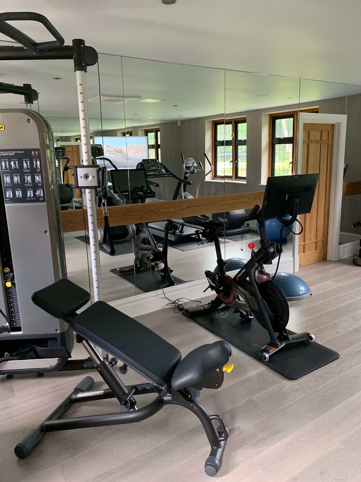 Photo of a mid-sized contemporary home weight room in Hertfordshire with grey walls, painted wood floors and beige floor.