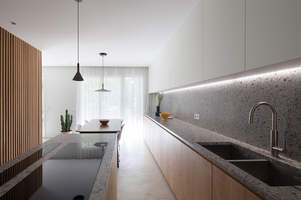 This is an example of a large contemporary single-wall open plan kitchen in Madrid with a double-bowl sink, flat-panel cabinets, light wood cabinets, terrazzo benchtops, multi-coloured splashback, panelled appliances, concrete floors, with island, grey floor and multi-coloured benchtop.