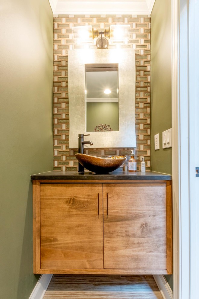 Design ideas for a small midcentury powder room in Other with flat-panel cabinets, medium wood cabinets, a one-piece toilet, multi-coloured tile, glass tile, green walls, ceramic floors, a vessel sink, engineered quartz benchtops, beige floor and black benchtops.