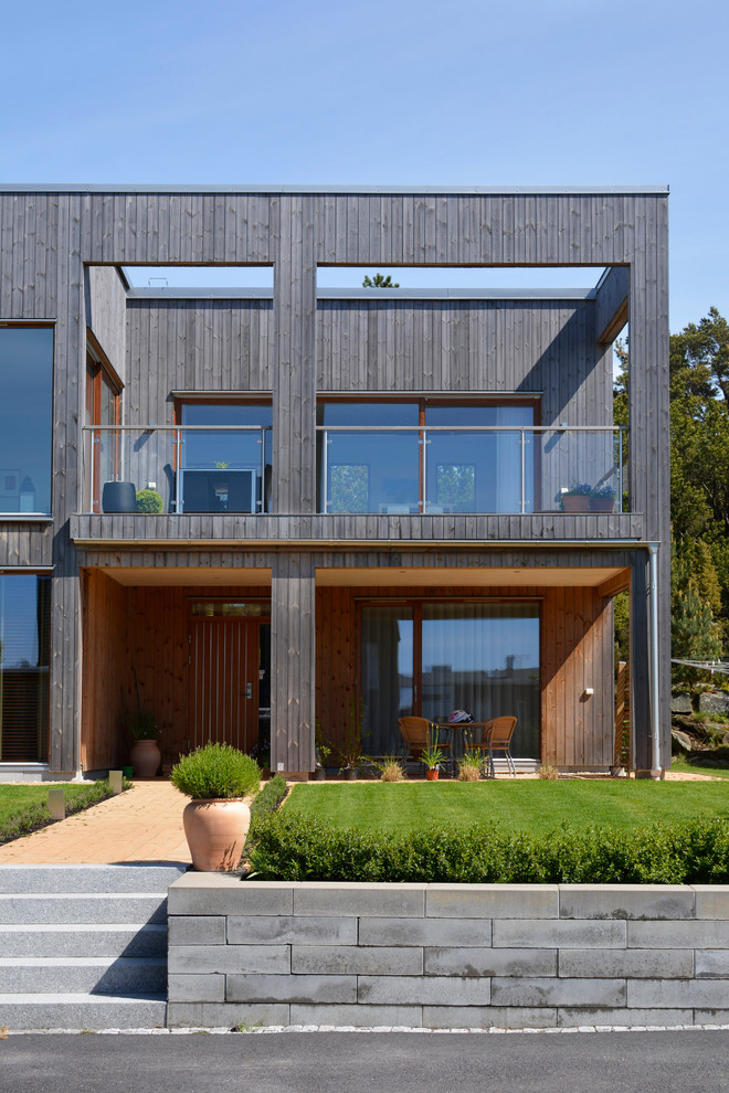 Inspiration for a large industrial two-storey black exterior in Gothenburg with wood siding and a flat roof.