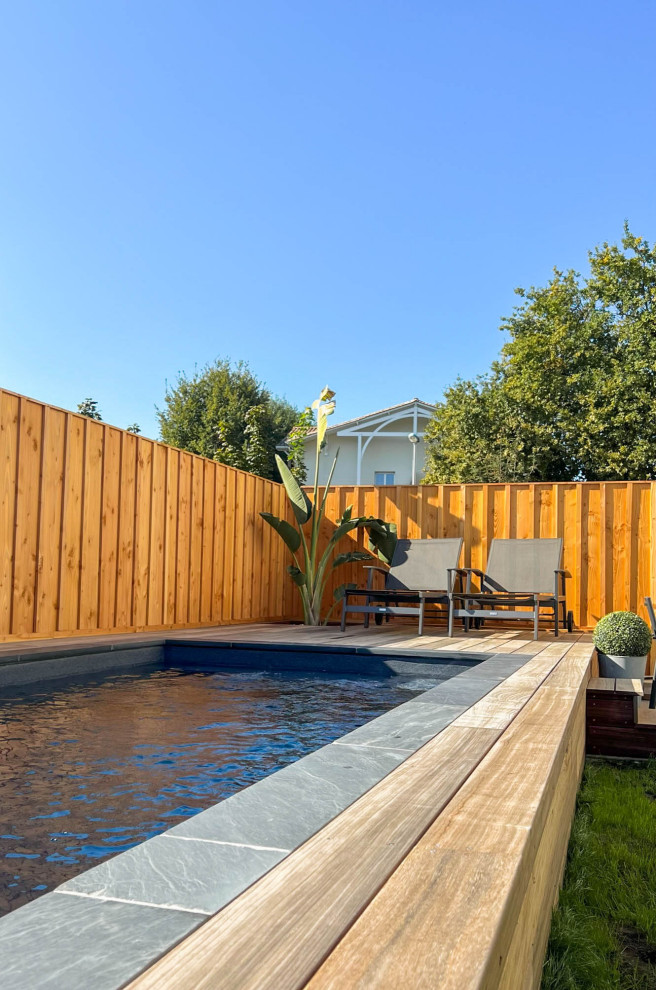 Ejemplo de piscina elevada minimalista pequeña rectangular en patio trasero con paisajismo de piscina y entablado