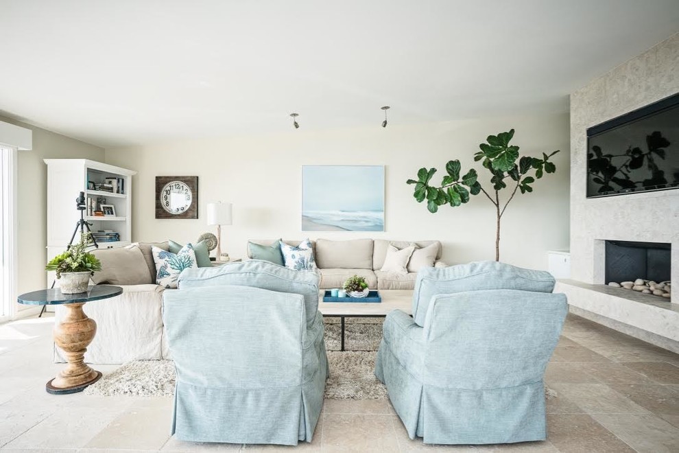 Design ideas for a mid-sized beach style enclosed family room in Orange County with beige walls, travertine floors, a standard fireplace, a stone fireplace surround, no tv and beige floor.