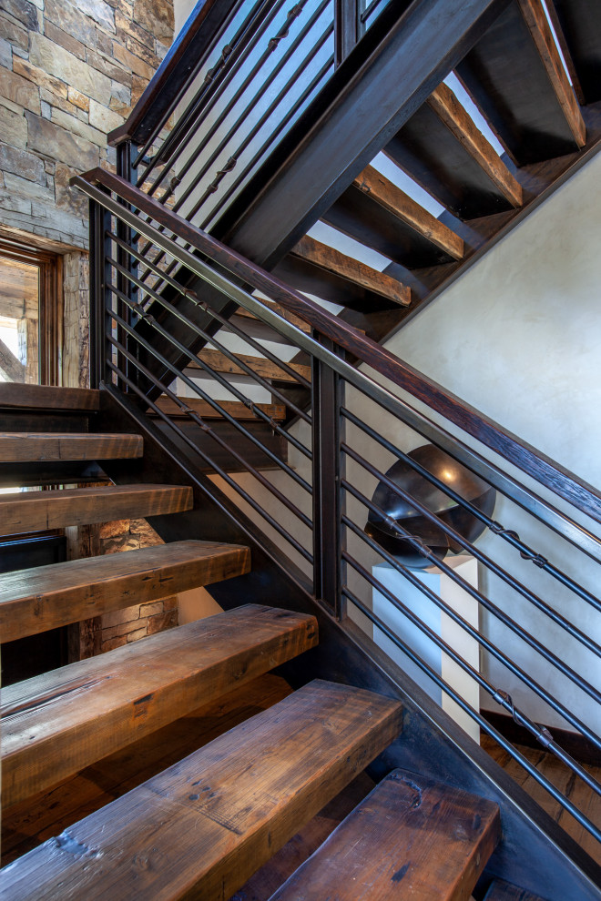This is an example of a large industrial wood u-shaped staircase in Denver with open risers and metal railing.