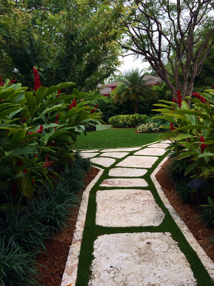 Photo of a large tropical side yard partial sun garden for summer in Miami with a garden path and natural stone pavers.