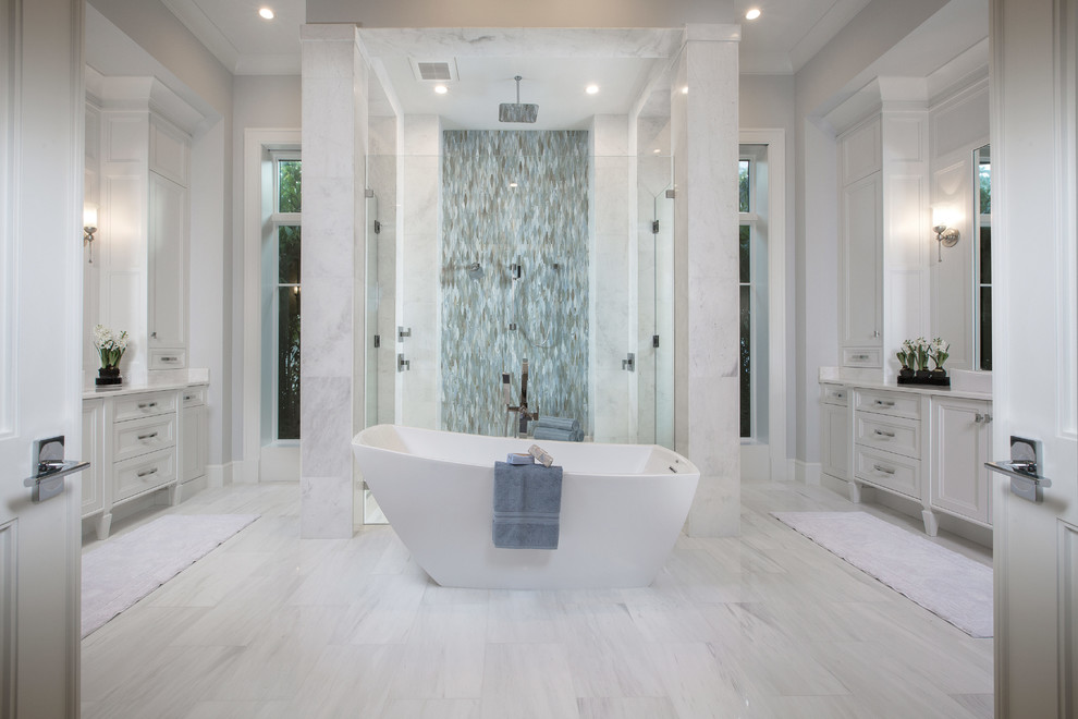 Example of a transitional master gray tile and white tile white floor freestanding bathtub design with recessed-panel cabinets, white cabinets, gray walls and a hinged shower door