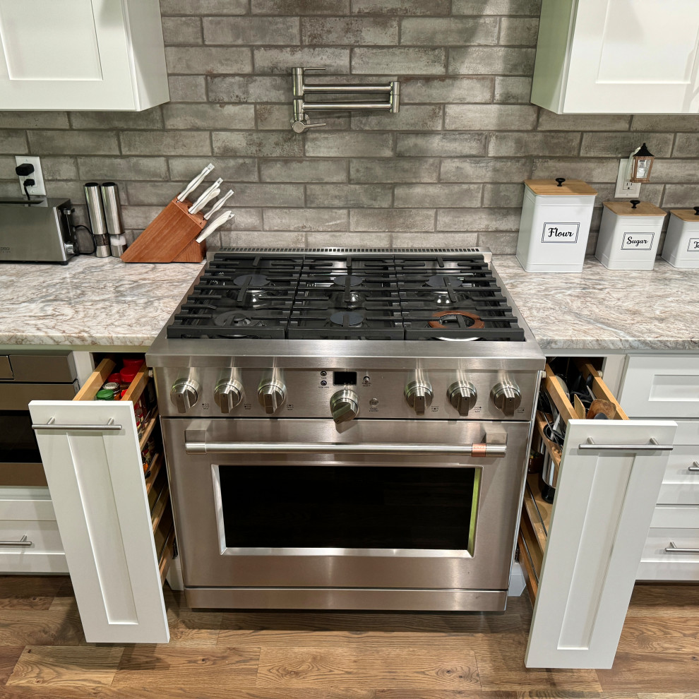 Inspiration for a transitional galley medium tone wood floor and brown floor eat-in kitchen remodel in Atlanta with an undermount sink, shaker cabinets, white cabinets, granite countertops, gray backsplash, ceramic backsplash, stainless steel appliances, an island and multicolored countertops