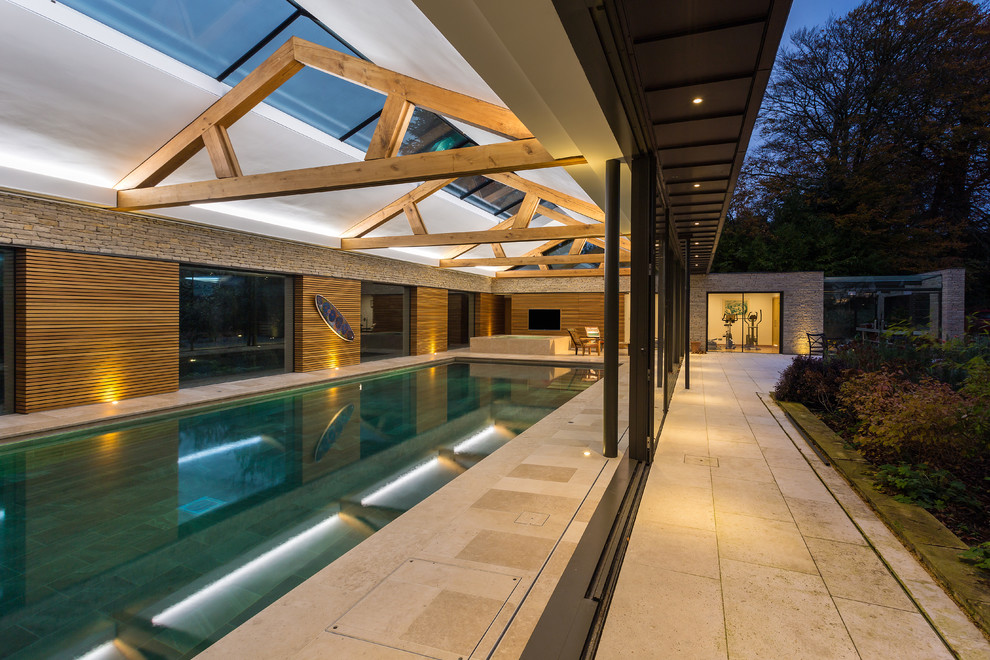 Large country indoor rectangular lap pool in Hampshire with a hot tub and natural stone pavers.